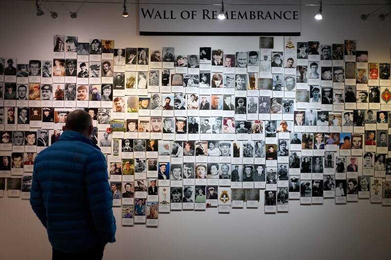 A visitor at a museum in Stanley, the capital of the Falklands, near a wall of photographs of British soldiers who died during the 1982 war for the islands.