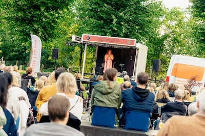 Twee cabaretoptredens bekijken op een klapstoel in de buitenlucht van Zeewolde