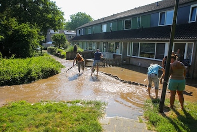 Water stroomt door straat in Apeldoorn na leidingbreuk, bewoners in de weer met zandzakken: ‘We doen