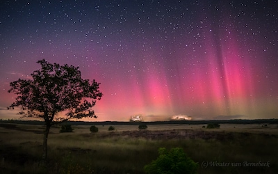 Waanzinnig beeld: rode en roze pilaren van licht boven de Veluwe