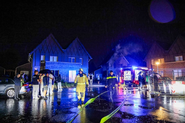 Local residents stand outside in the pouring rain, watching as their new neighbors' house was destroyed by the flames. 
