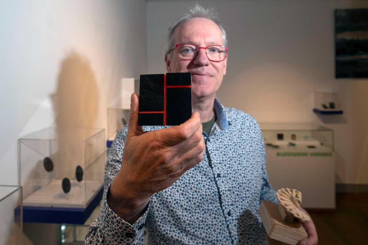Paul Albers met twee excentrieke penningen, waaronder een kunstwerk van Olivier Julia (zwart met rood).