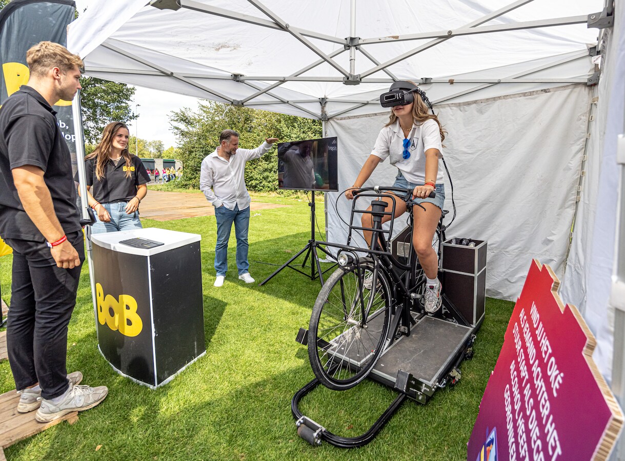 Eerstejaars hbo-studenten nemen tijdens het introductiekamp in Zwolle plaats op een testfiets met VR-bril, om zo virtueel te ervaren hoe je fietst als je drank op hebt.
