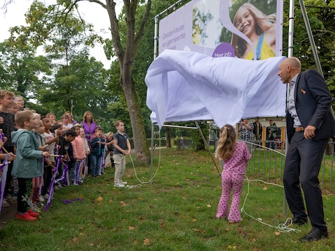 Jip uit groep 5 (links bij het doek) mag samen met wethouder Jasper Bloem de nieuwe naam onthullen.